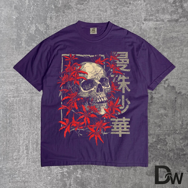 May include: A purple t-shirt with a skull graphic and red leaves. The skull is detailed with shading and a spiderweb design. Japanese characters are printed on the right side of the skull. The shirt has a crew neck and short sleeves.