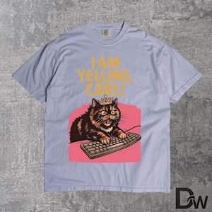 Pode incluir: Camiseta azul claro com um gato de desenho animado usando uma coroa e um teclado. O texto "I AM YELLING, CARL!" &eacute; impresso em amarelo acima do gato. O gato est&aacute; em um fundo rosa.