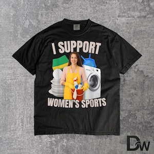 Puede incluir: Camiseta negra con el texto "I SUPPORT WOMEN'S SPORTS". El gráfico incluye una mujer con un delantal amarillo sosteniendo productos de limpieza, junto con una lavadora, platos y herramientas de limpieza.