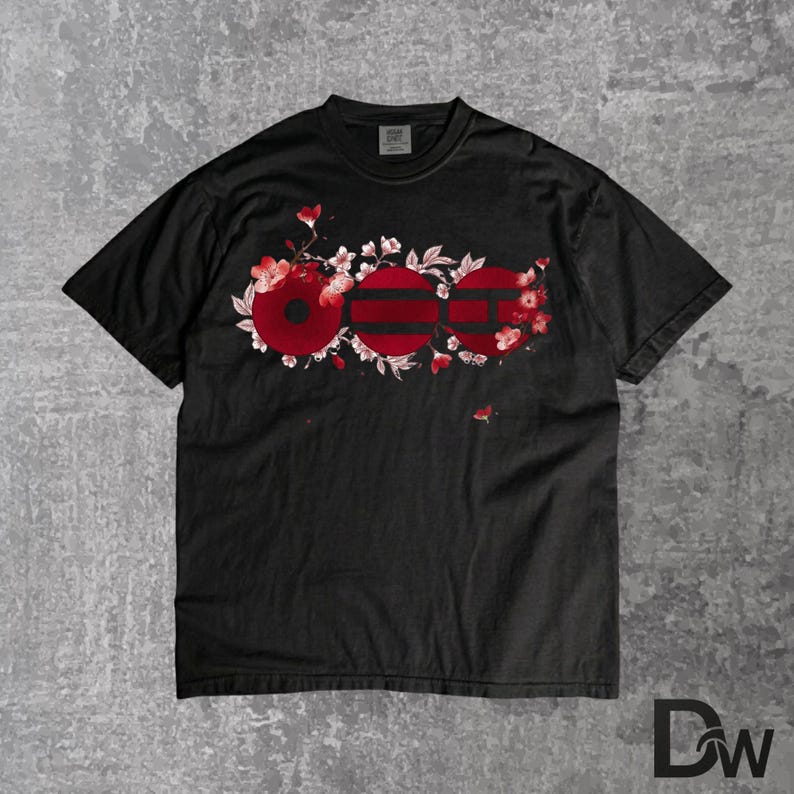 May include: Black t-shirt featuring a floral design with the letters "OOO" in red. The letters are stylized as circles with horizontal stripes. The design is surrounded by red flowers and white blossoms.