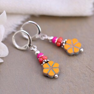 Puede incluir: Pendientes colgantes con cuentas en forma de flor naranja y detalles azules. Los pendientes tienen aros plateados y están adornados con cuentas rosas y rojas. Los pendientes están diseñados para orejas perforadas.