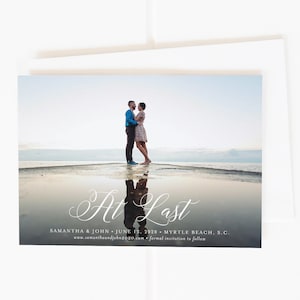 May include: A wedding announcement card with a photo of a couple embracing on a beach. The text reads "At Last" with the couple's names, wedding date, location, and website.