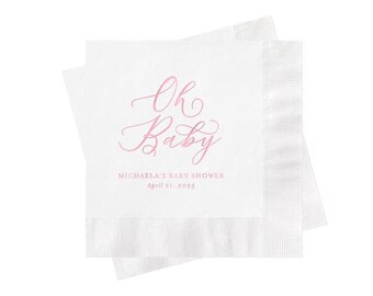 May include: Two square white paper napkins stacked at an angle. The top napkin features the pink script text Oh Baby, followed by the printed text MICHAELA'S BABY SHOWER and the date April 21, 2025, in a smaller, simple pink font.