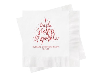 May include: A white square paper napkin featuring red text that reads 'tis the season to sparkle' arranged in a tree shape, with the text 'HUBBARD CHRISTMAS PARTY' and '12.19.25' printed in red below the design on a textured paper surface.