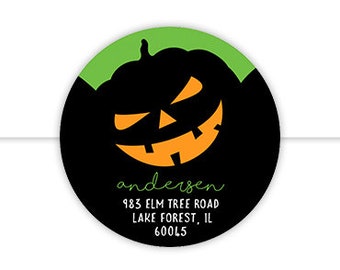 May include: A round sticker with a black background and a green border. A black and orange jack-o'-lantern face is in the centre. The text "Andersen" is below the jack-o'-lantern, followed by the address "983 Elm Tree Road, Lake Forest, IL 60045".
