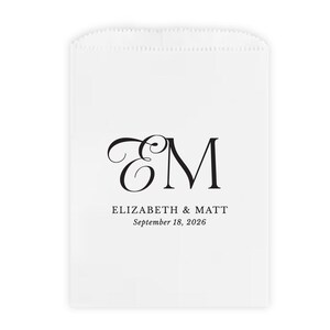 May include: White favor bag with a black monogram of the letters "E" and "M". Below the monogram are the names "Elizabeth & Matt" and the date "September 18, 2026" in a simple font. The bag has a scalloped top edge.
