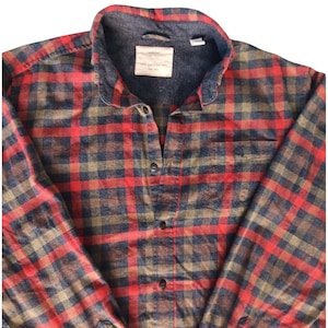 May include: A white ceramic mug with a black handle and the text "But First, Coffee" in a bold, black font. The mug is set against a blurred background, highlighting its clean design.