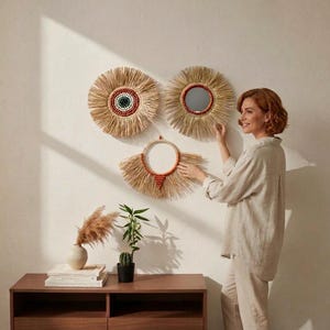 May include: Three circular wall decorations made of natural straw fibers. Two are full sunburst shapes, one featuring a central mirror and the other a multi-colored beaded center. The third is a semi-circular fan shape with orange beads.