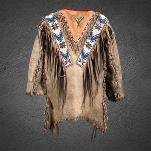 May include: A tan suede jacket with long fringe and beaded accents. The jacket features a V-neck collar with a red trim and a decorative beaded pattern in blue, white, and red. The sleeves and hem are fringed.