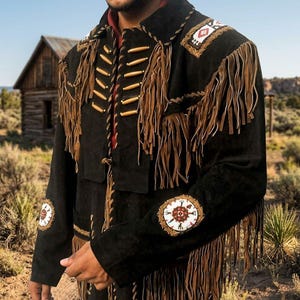 May include: Black suede jacket with brown fringe and decorative beadwork. The jacket features tan leather fringe along the sleeves, chest, and back. The shoulders and sleeves have circular and rectangular beaded patches.