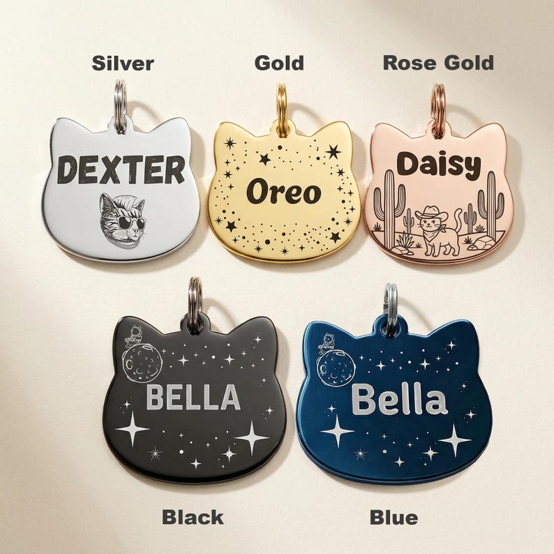 Peut inclure: Cinq m&eacute;dailles pour animaux en forme de t&ecirc;te de chat, disponibles en finitions argent, or, or rose, noir et bleu. Chaque m&eacute;daille poss&egrave;de un anneau m&eacute;tallique et des gravures personnalis&eacute;es : Dexter avec un chat, Oreo avec des &eacute;toiles, Daisy avec des cactus, et deux m&eacute;dailles Bella avec des motifs de lune et d'&eacute;toiles.