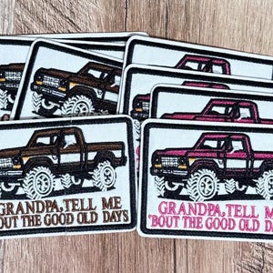 May include: A collection of rectangular embroidered patches featuring a pickup truck illustration. One patch shows a brown truck with brown text reading "GRANDPA, TELL ME 'BOUT THE GOOD OLD DAYS," while another shows a pink truck with pink text.