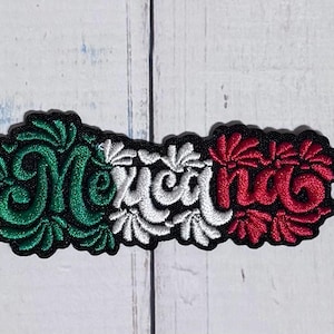 May include: An embroidered patch featuring the word Mexicana in a stylized script font. The embroidery uses a color scheme of green, white, and red, arranged in vertical segments that mimic a flag. The lettering is outlined in black thread.