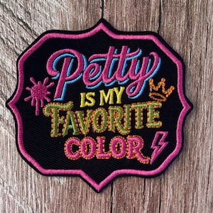 May include: A black embroidered patch with a pink scalloped border featuring the text "Petty IS MY FAVORITE COLOR" in pink, yellow, and green thread. The design includes a small pink sunburst, an orange crown, and a pink lightning bolt icon.