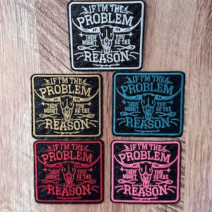 Peut inclure: Cinq écussons carrés brodés présentant un motif central de crâne de bœuf et le texte IF I'M THE PROBLEM THEN YOU MIGHT BE THE REASON. Les écussons sont disponibles avec des fils blancs, dorés, bleu sarcelle, rouges et roses sur fond noir.