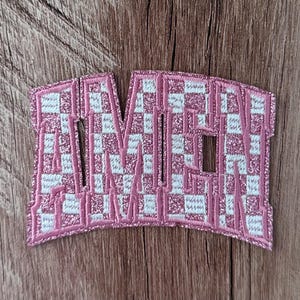 May include: An embroidered patch featuring the word AMEN in a bold, block-style font. The letters are filled with a pink and white checkered pattern and outlined with a shimmering pink glitter thread border, creating a distinct textured appearance.