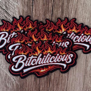 May include: Three embroidered patches featuring the word Bitchilicious in white cursive script with a black outline. The text is surrounded by stylized orange, yellow, and red flames with a black border, creating a bold and fiery graphic design.
