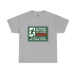 May include: A heather grey short-sleeve t-shirt featuring a rectangular green sign graphic with a white running figure icon. The text reads: WE SHOULDN'T HAVE TO WAIT FOR A NATIONAL TRAGEDY TO HEAL A DIVIDE OUR LEADERS CREATED, with TRAGEDY in red.