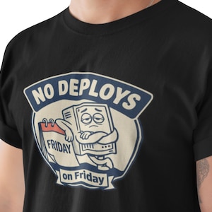 May include: Black t-shirt featuring a cartoon computer character with a sad expression, hugging itself. The design includes the text "NO DEPLOYS" above and "on Friday" below, with "FRIDAY" on a calendar.