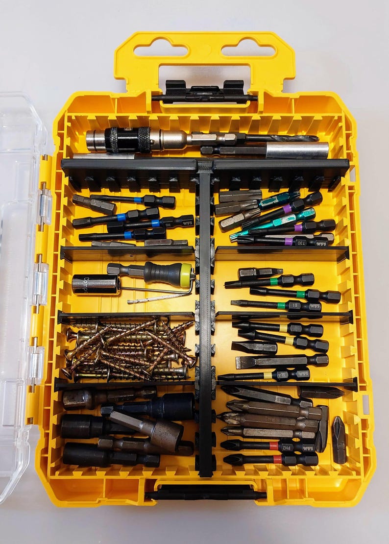 May include: A yellow toolbox filled with various screwdriver bits, sockets, and screws. The case is divided into compartments, offering organized storage for different tools. The tools are in various colors, including black, silver, and green.