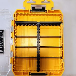 May include: Yellow and black tool organizer with a clear plastic lid. The organizer has multiple compartments and a handle for easy carrying. The brand name "DEWALT" is visible on the clear lid. The interior is divided into sections for storing tools.