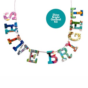 May include: A colorful paper garland that spells out "Shine Bright" with a white background. The garland is strung on a red and white twine. A teal circle with the text "Shine Bright Garland Kit" is in the upper right corner of the image.