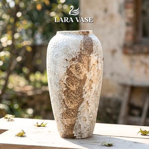 May include: A tall, textured vase with a weathered appearance. The vase features a mix of brown and white tones, creating a rustic aesthetic. The vase is cylindrical with a slightly flared top, suitable for floral arrangements or as a decorative piece.