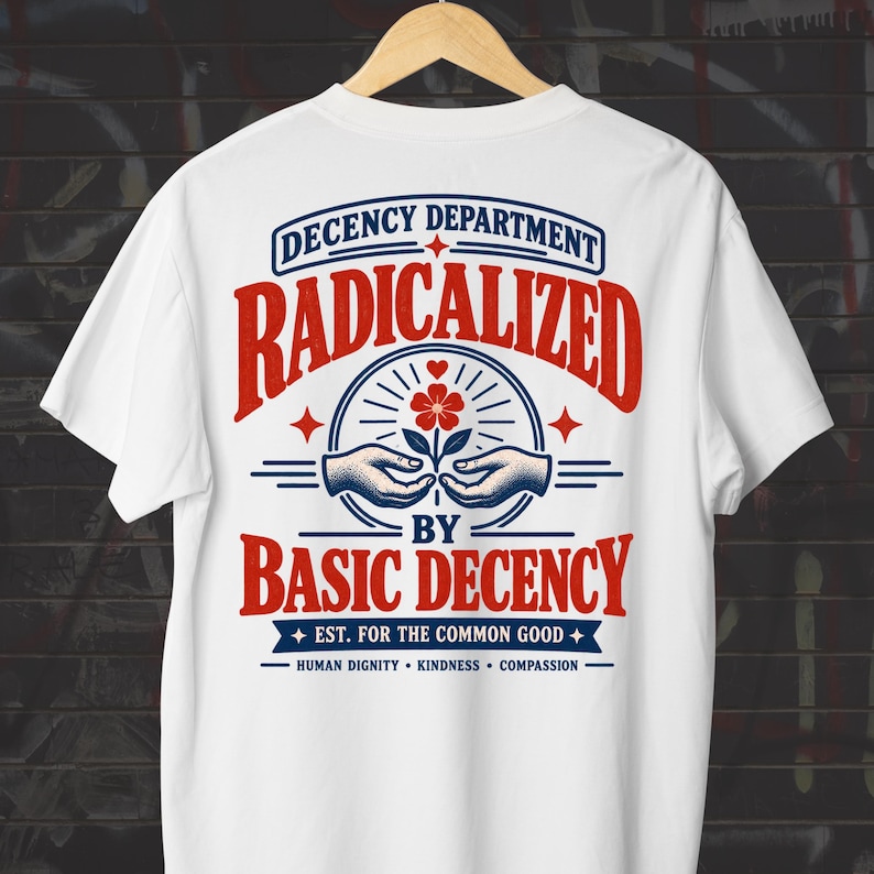 May include: A white t-shirt featuring a graphic on the back with the text "DECENCY DEPARTMENT RADICALIZED BY BASIC DECENCY EST. FOR THE COMMON GOOD HUMAN DIGNITY KINDNESS COMPASSION" in red and blue, with an illustration of hands holding a flower.