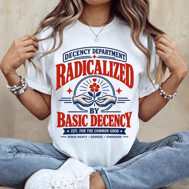 Vintage-inspired “Radicalized by Basic Decency” digital design featuring bold red and navy typography, a “Decency Department” emblem, helping hands holding a flower, decorative stars, and a banner reading “Est. for the Common Good,” with “Human Dignity • Kindness • Compassion” beneath. The artwork has a distressed retro screen-print aesthetic on a transparent background.
