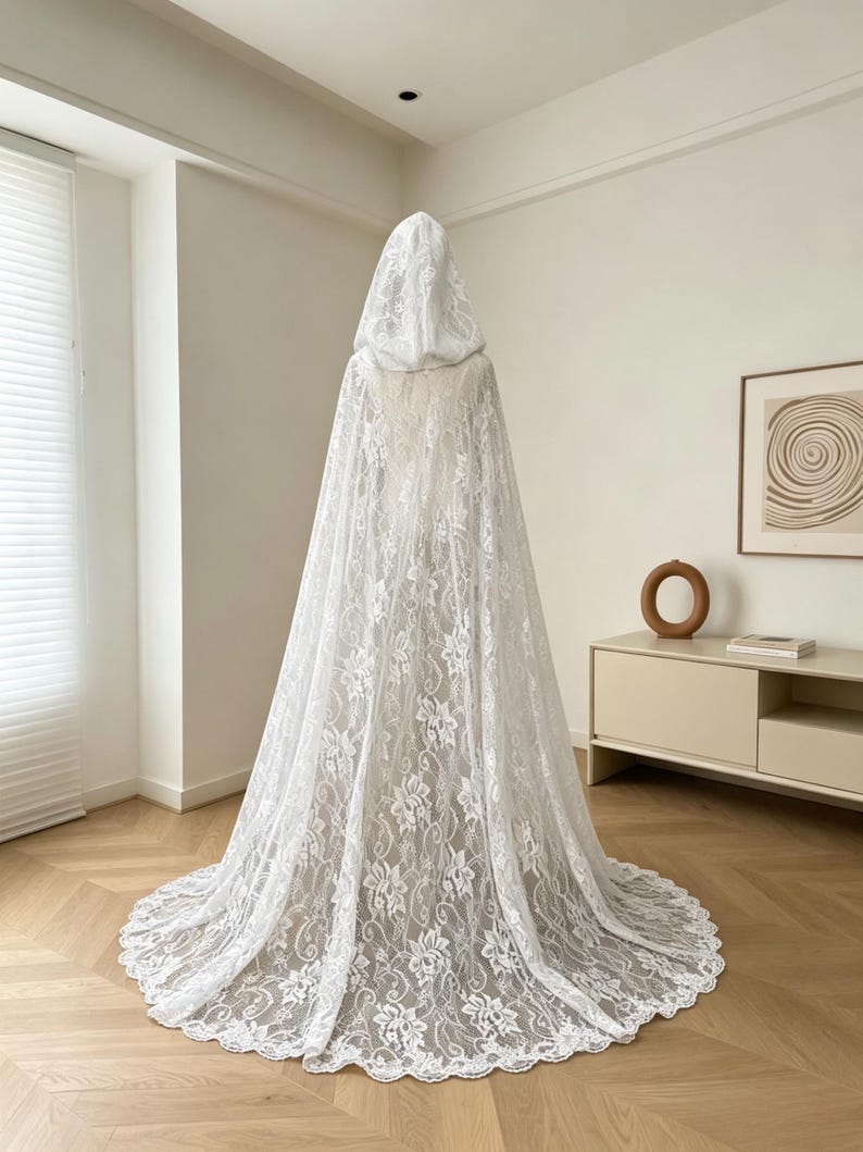 May include: A white lace hooded cape with a floral pattern. The cape is long, flowing, and covers the entire body. The hood is also made of lace and is attached to the cape. The cape is designed to be worn over clothing.