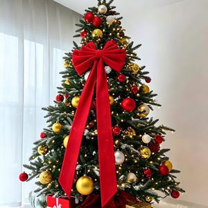 Op de afbeelding: Een versierde kerstboom met een grote rode fluwelen strik, gouden en rode kerstballen en warmwitte kerstverlichting. Een gouden ster siert de top, terwijl rood en goud ingepakte cadeaus aan de voet van de boom staan.