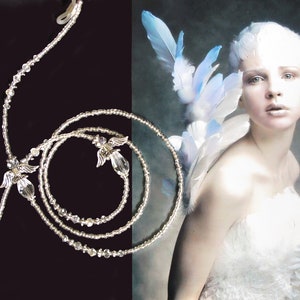May include: A silver beaded necklace with angel wing charms. The necklace is layered and has a clasp closure.