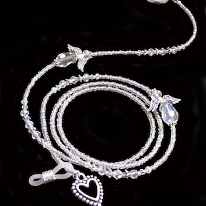 May include: A silver eyeglass chain with clear crystal beads and angel wing charms. The chain has a heart-shaped charm at the bottom.