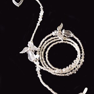 May include: A silver eyeglass chain with clear beads and angel wing charms. The chain has a heart charm at the top and clear bead accents.