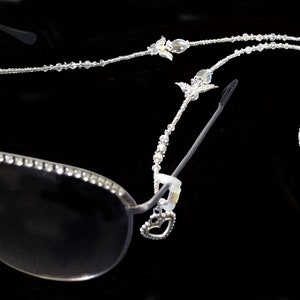 May include: Silver aviator sunglasses with a crystal-encrusted frame and a crystal beaded chain.
