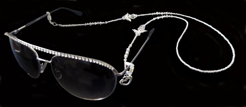 May include: Silver aviator sunglasses with a crystal-encrusted frame and a crystal beaded chain.