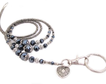 May include: A silver beaded lanyard with a heart charm and a silver swivel clasp. The beads are black and gray.
