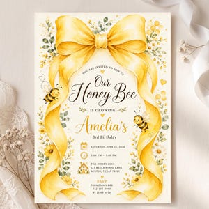 Könnte beinhalten: Eine rechteckige Geburtstagseinladungskarte mit einer großen gelben Aquarell-Schleife oben, zwei gezeichneten Bienen und Blumenmotiven. Der Text lautet: Our Honey Bee is growing, Amelia's 3rd Birthday, Saturday, June 21, 2026, 2:00 PM - 5:00 PM, The Honey Hive, 123 Beechwood Lane, Austin, Texas 78701, RSVP to Mommy Bee 512-555-7890 by June 10th.