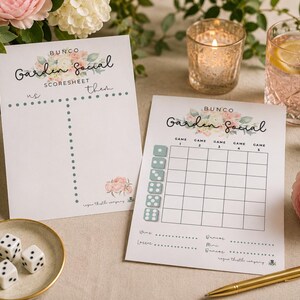 May include: Two white paper Bunco Garden Social scoresheets featuring floral illustrations, a grid for five games, and columns for us and them. The sheets include the text Bunco Garden Social, Scoresheet, and Rogue Thistle Company.