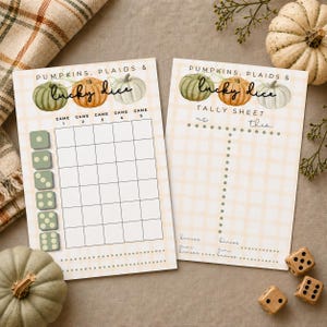 May include: Two printed game score sheets featuring a light beige plaid background and watercolor pumpkin illustrations. The left sheet is titled Pumpkins, Plaids & Lucky Dice with a grid for five games. The right sheet is a Tally Sheet labeled Us and Them.