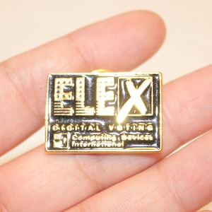 Peut inclure: Une épingle rectangulaire dorée avec des détails en émail noir. L'épingle présente le mot "FLEX" avec un "X" blanc et le texte "DIGITAL VOTING Computing Devices International".