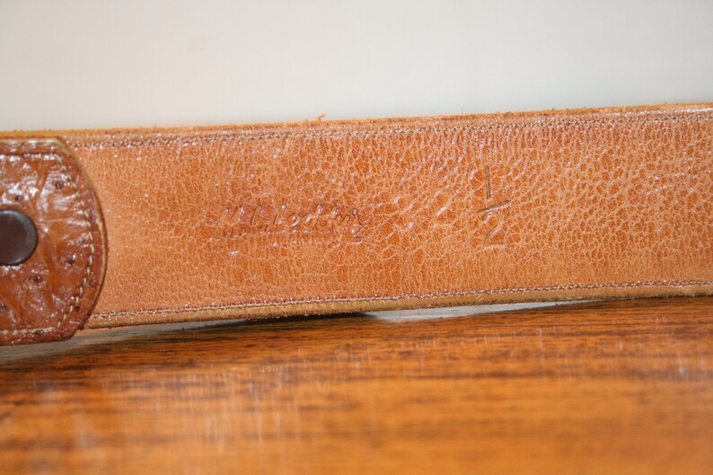 Op de afbeelding: Close-up van een bruine leren riem met de tekst "Westerly" en het nummer "12" gegraveerd op de achterkant.