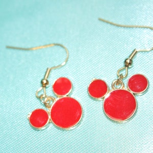 May include: A pair of gold dangle earrings with red Mickey Mouse head charms.