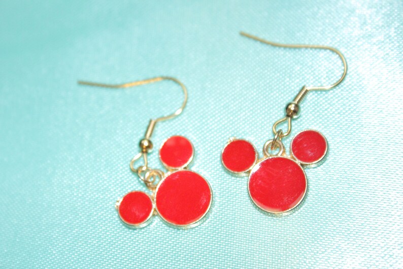 May include: A pair of gold dangle earrings with red Mickey Mouse head charms.