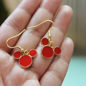 May include: A pair of gold dangle earrings with red enamel Mickey Mouse heads.