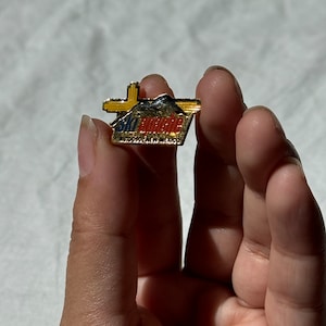 Può includere: Uno spillo dorato con le parole "Ski Apache" e "Ruidoso, Nuovo Messico" in lettere rosse, blu e gialle.