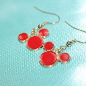 May include: Red and gold Mickey Mouse-shaped earrings. The earrings have three red circles on each side.