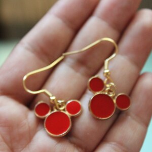 May include: Gold dangle earrings with red Mickey Mouse head charms.