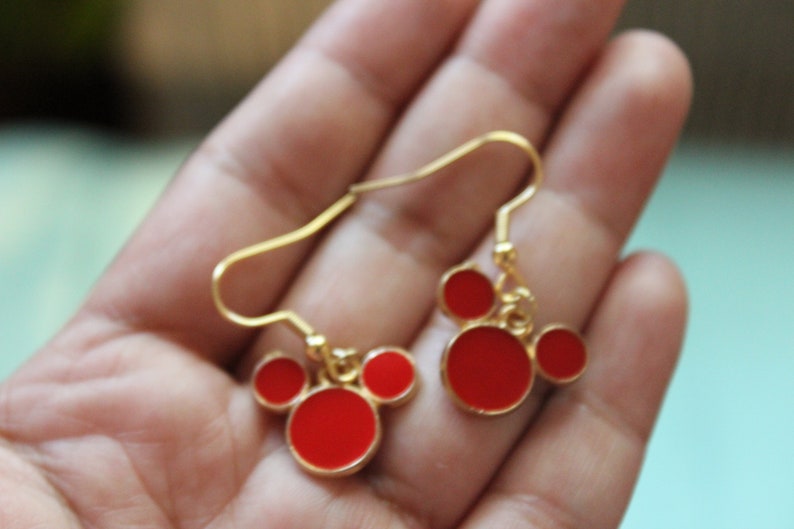 May include: Gold dangle earrings with red Mickey Mouse head charms.
