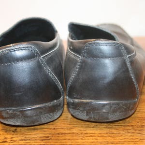 Puede incluir: Un par de zapatos negros de cuero sin cordones con punta redonda.
